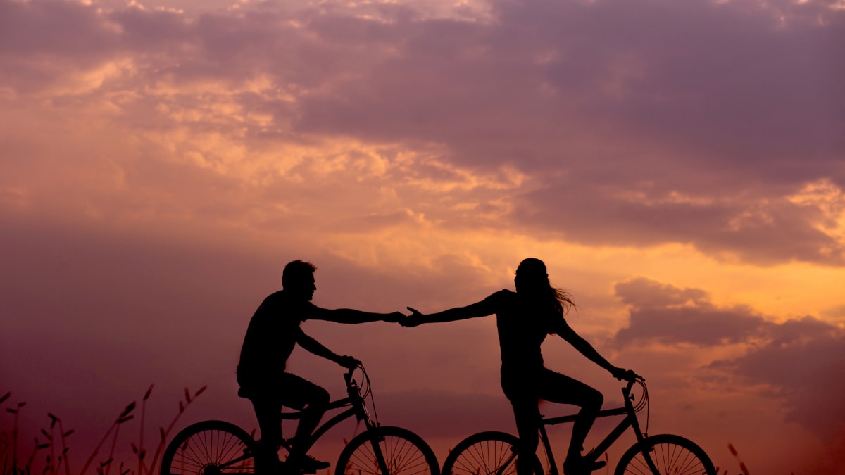 woman on bike reaching for man's hand behind her also on bike